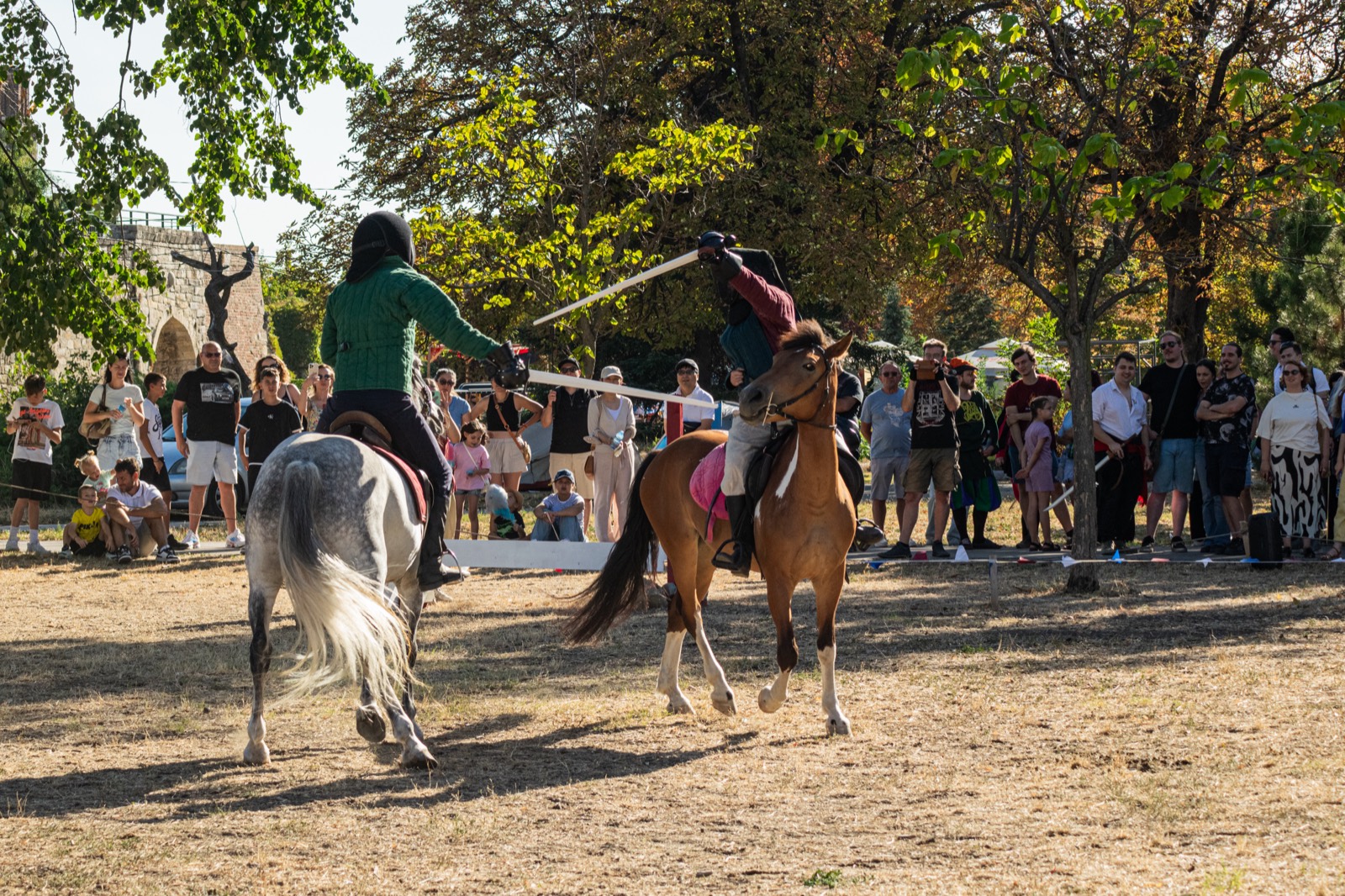 Two riders fencing on horseback in the Mounted HEMA tournament, watched by a crowd